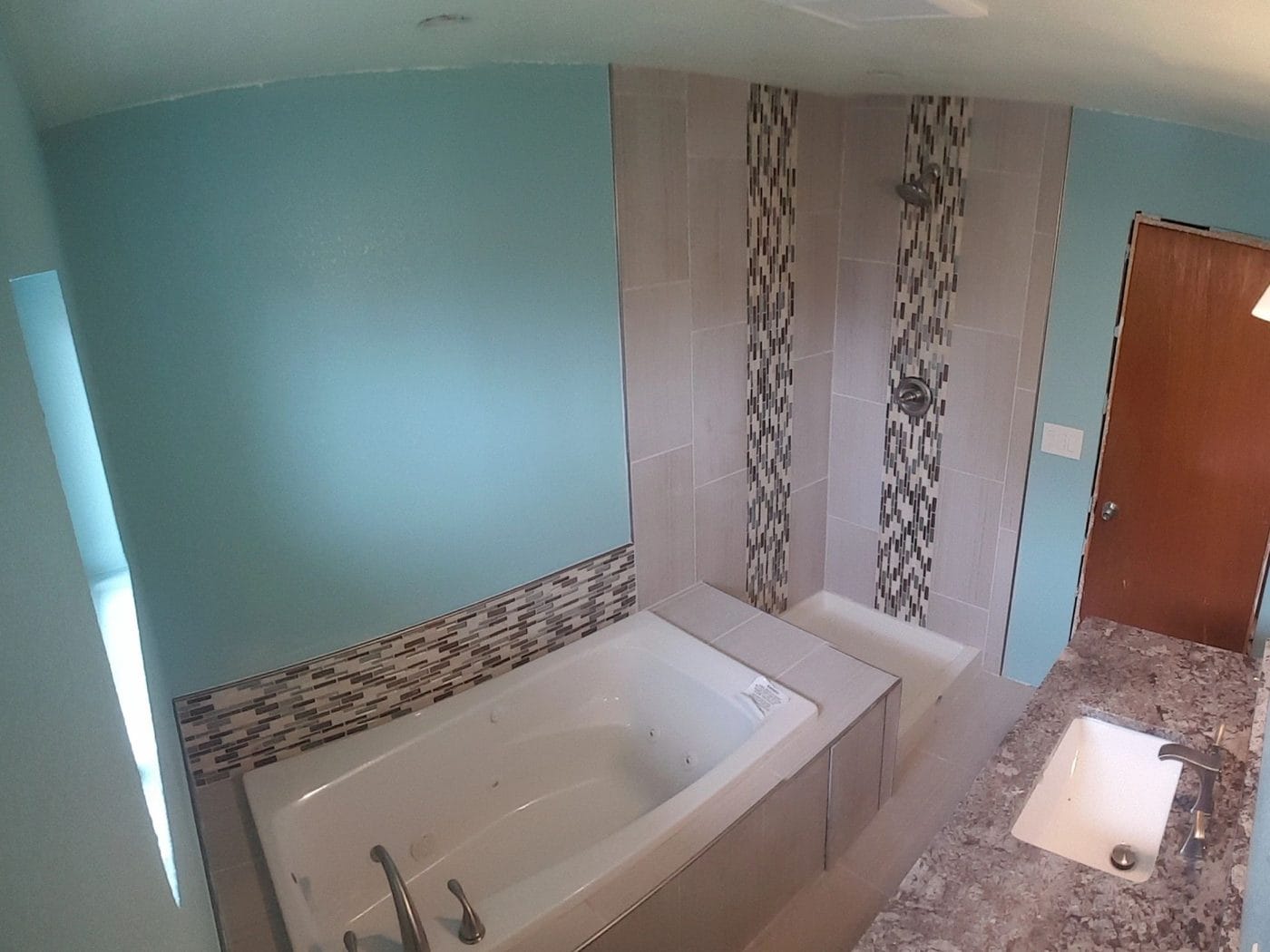 A soaking tub set into tile with a mosaic band up the wall