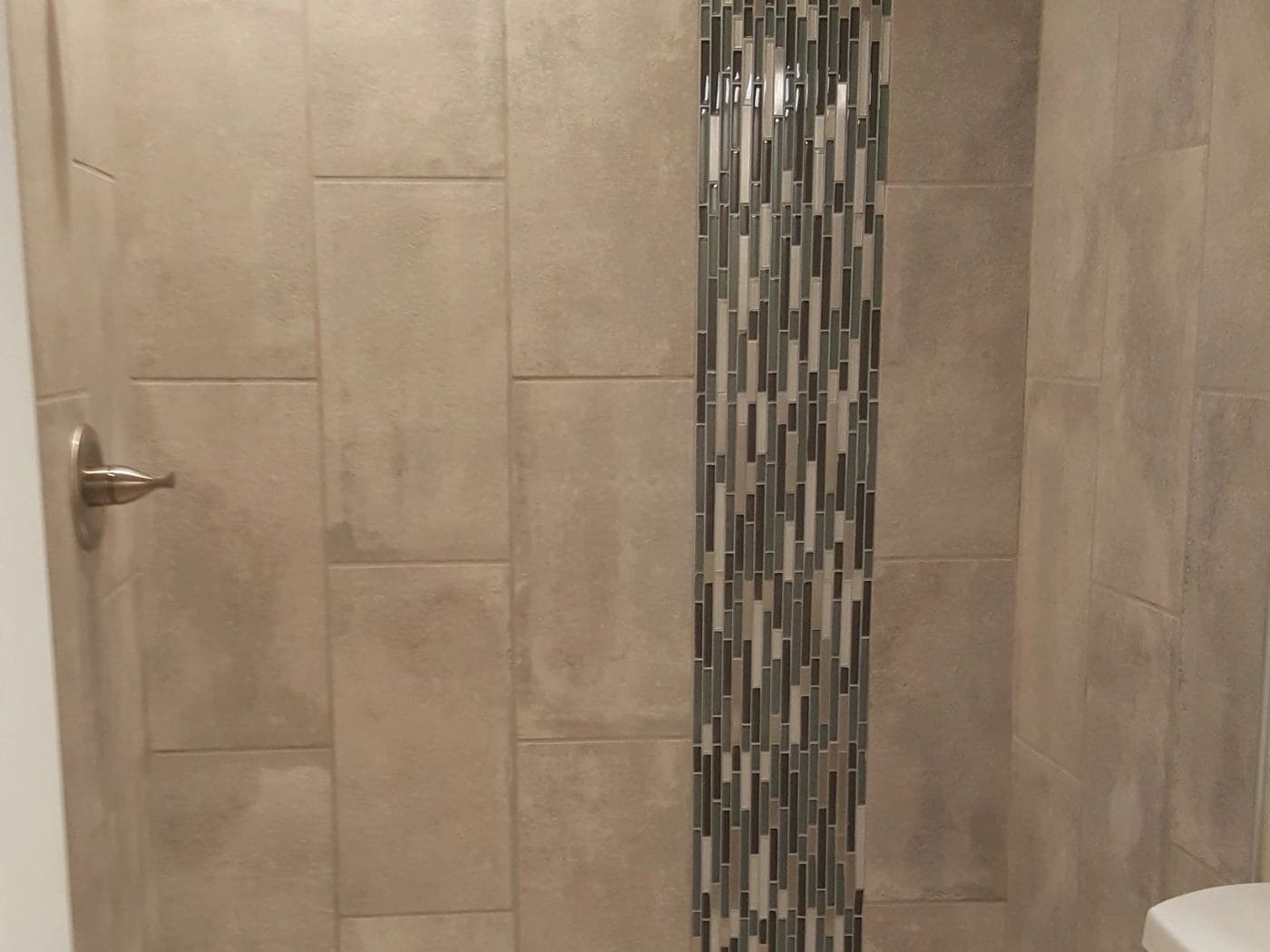 A tub and shower with a vertical mosaic inlay
