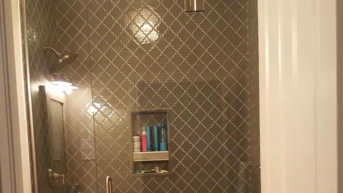 A finished bathroom with a fully tiled shower, a glass door and a built-in niche