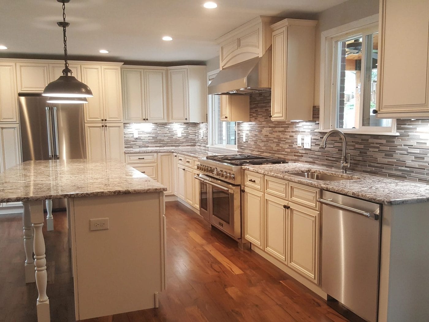 A kitchen with cream cabinetry, a granite island and a hardwood floor