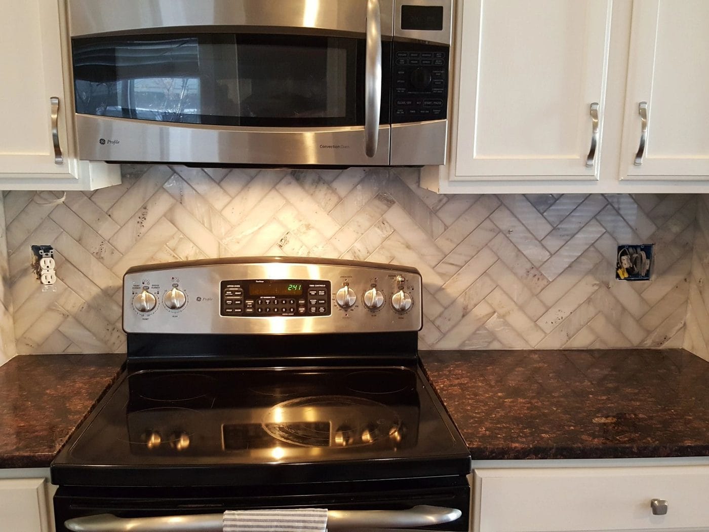 A herringbone tile backsplash behind a range