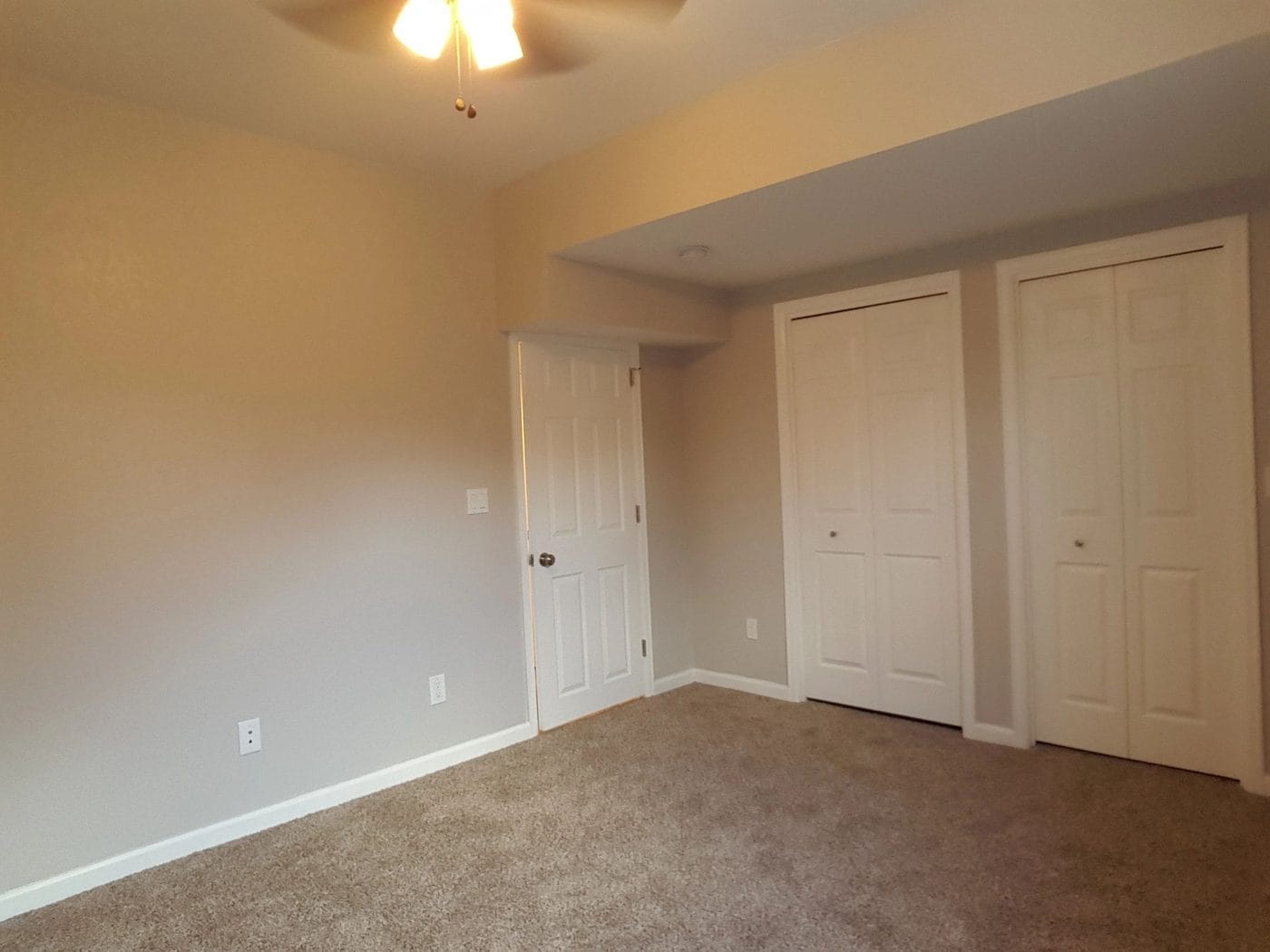 A finished basement room with new carpet and closet doors