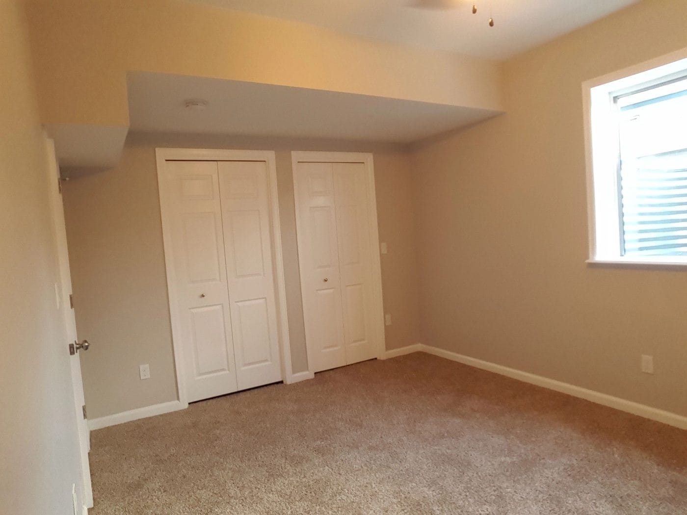 A finished basement room with double closet doors and a window