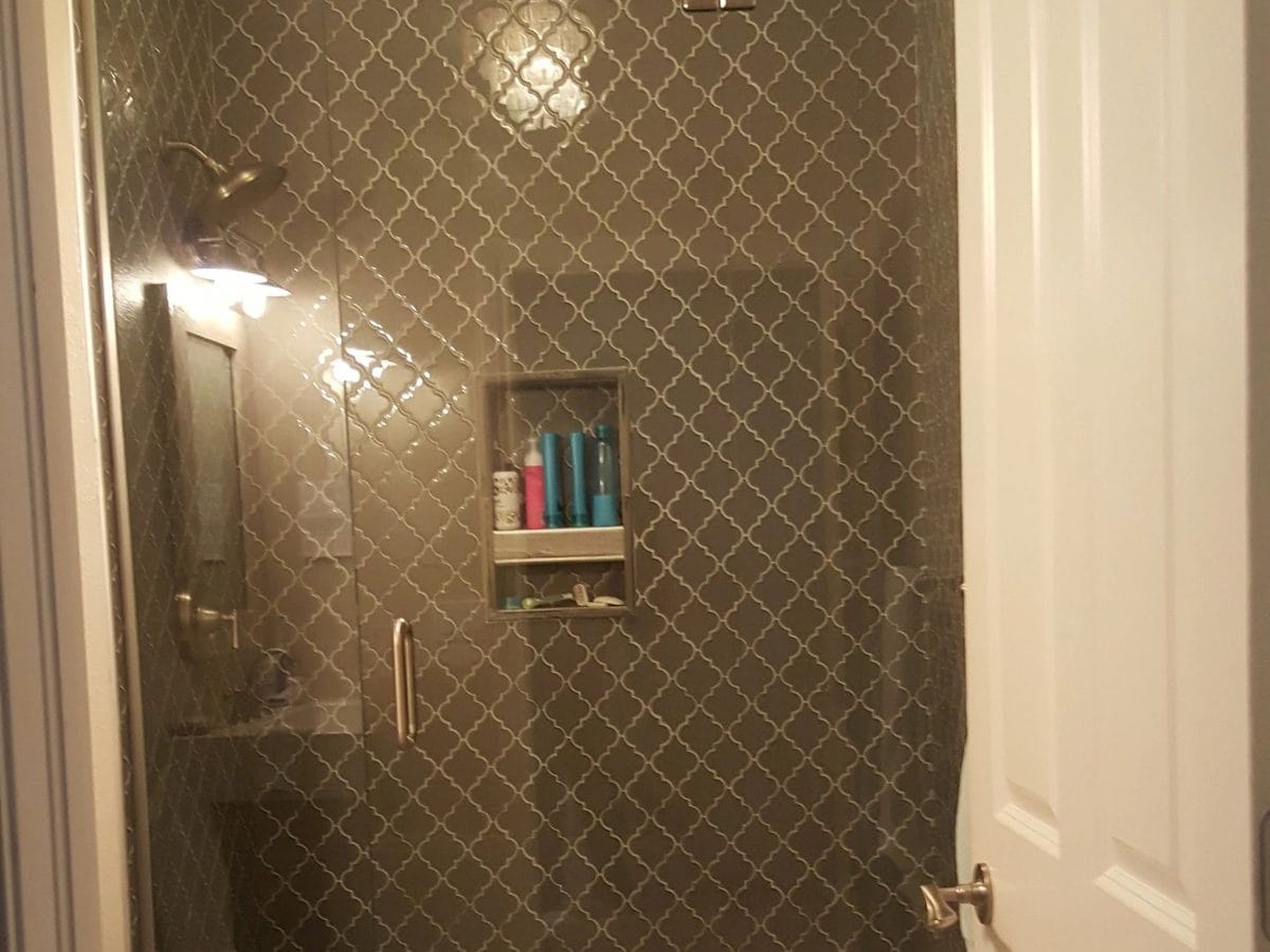 A finished bathroom with a fully tiled shower and a glass door