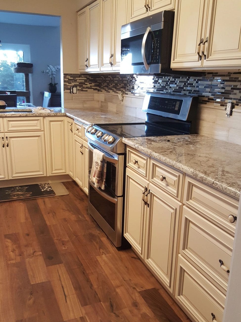 A finished kitchen with cream cabinetry, granite counters and stainless appliances